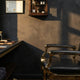 A professional barbershop station featuring a black leather chair with gold hardware and neatly arranged grooming tools under dramatic editorial lighting.