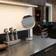 A clean and precisely organized minimalist barber workstation with professional clippers and tools neatly arranged on a sleek countertop in a modern barbershop setting.